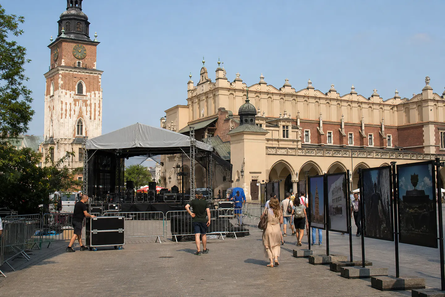 Event crews preparing a temporary stage in Krakow as pedestrians cross the square