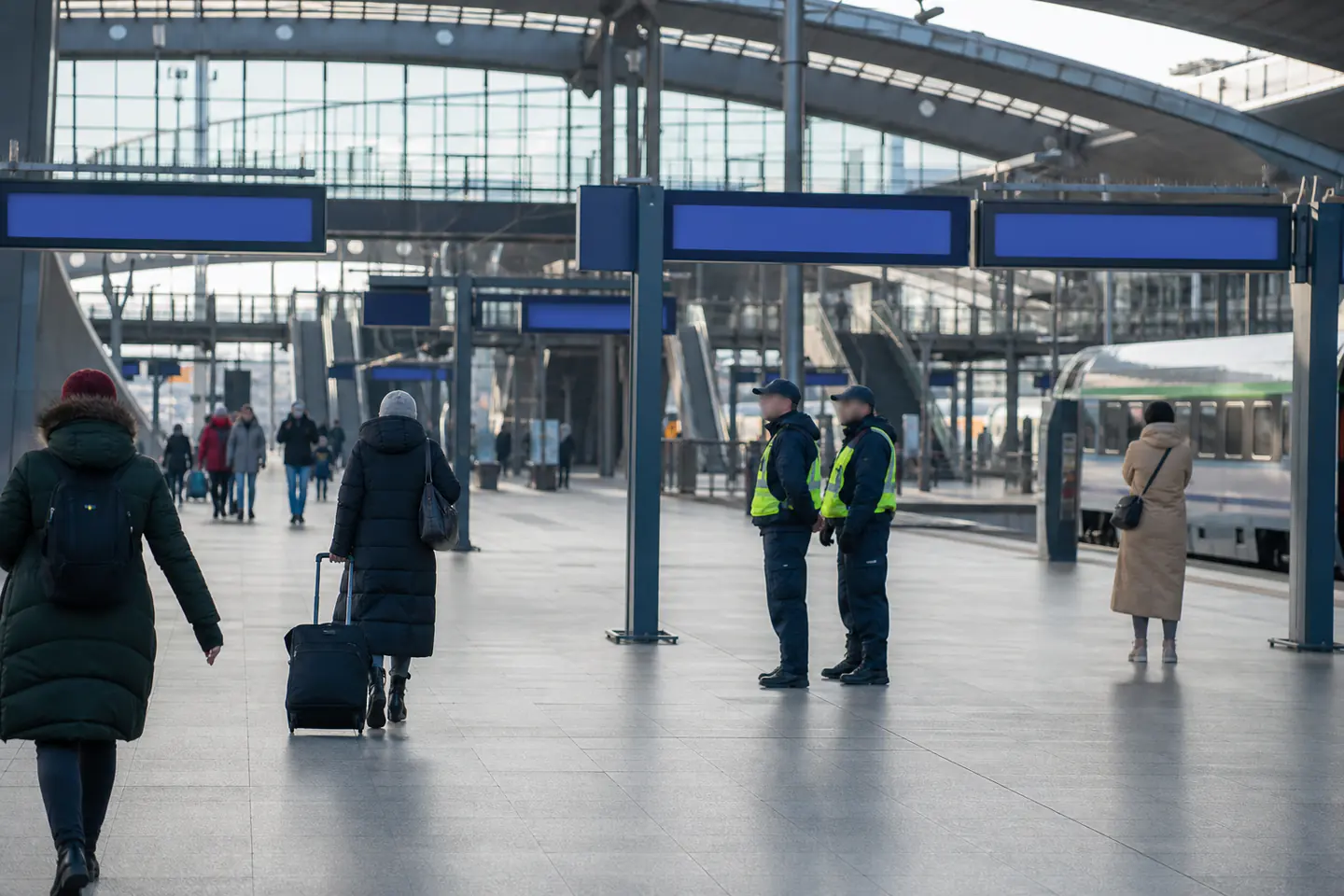 Travelers and security staff during normal operations at a Polish railway station